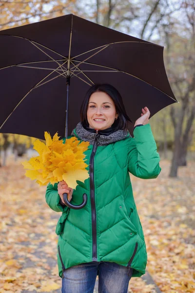 Gyönyörű fiatal nő zöld kabát gazdaság levelek — Stock Fotó