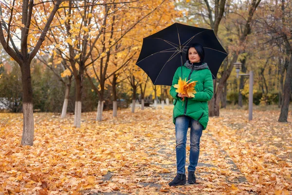 Alleenstaande vrouw wandelen tussen gevallen bladeren — Stockfoto