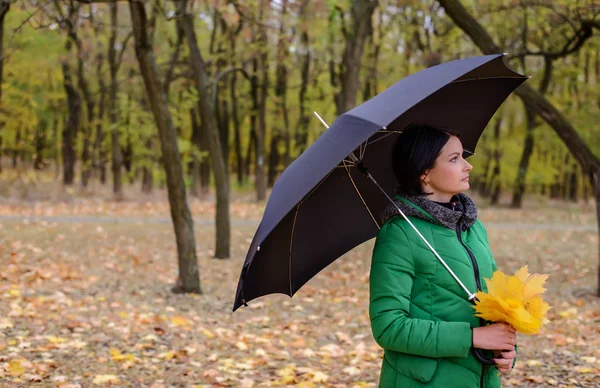 Single woman standing on sidewalk with leaves — Stock Photo, Image