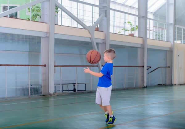 Jonge jongen spelen basketbal op een indoor baan Rechtenvrije Stockafbeeldingen