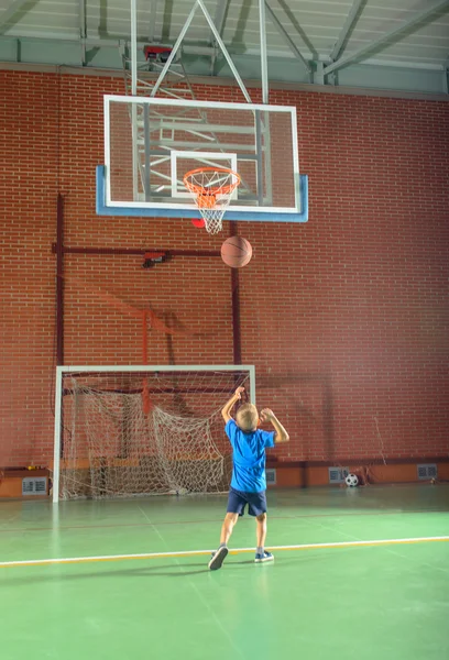 Молодий хлопчик стріляє по воротах у баскетбол Стокова Картинка