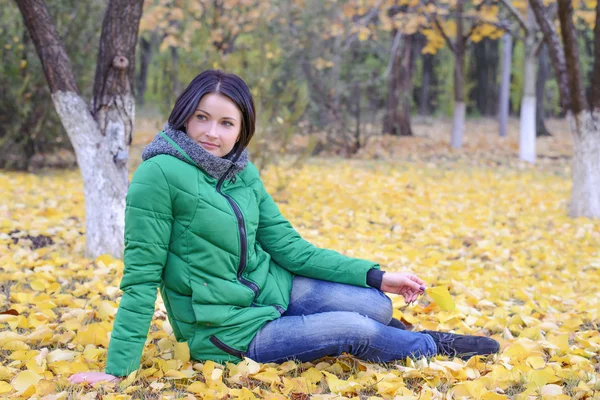 Ruhige Frau sitzt auf dem Boden zwischen Blättern — Stockfoto