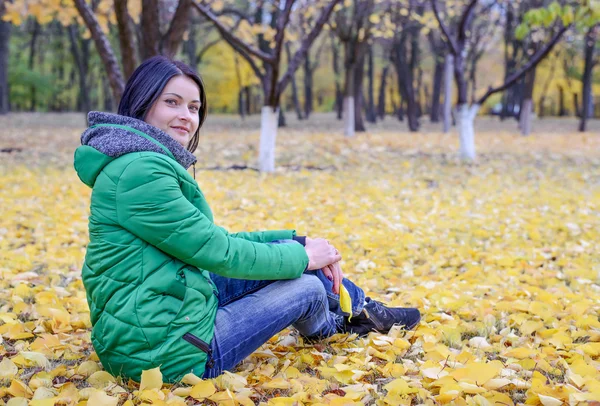 Ruhige Frau sitzt auf dem Boden zwischen Blättern — Stockfoto