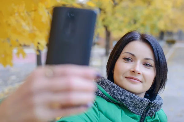 Gorgeous lady taking picture of herself near tree — Stock Photo, Image