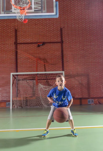 Sportig liten pojke spela basket Stockbild