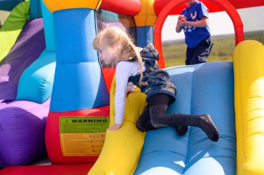 Bir slayt üzerinde oynayan sevimli küçük sarışın kız