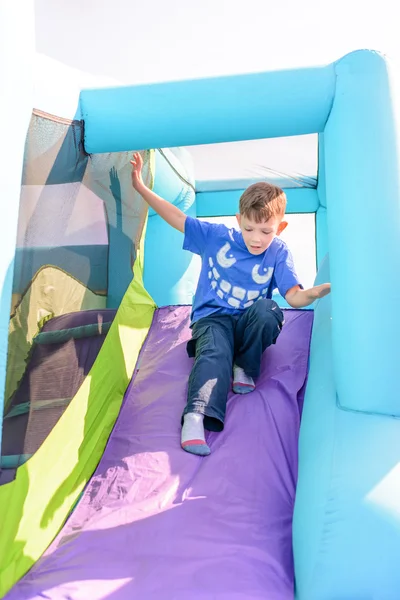 Leuke jongen glijdend van opblaasbare rit — Stockfoto