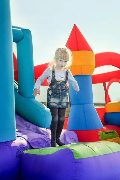 Menina feliz na parte inferior da corrediça bouncy inflável — Fotografia de Stock