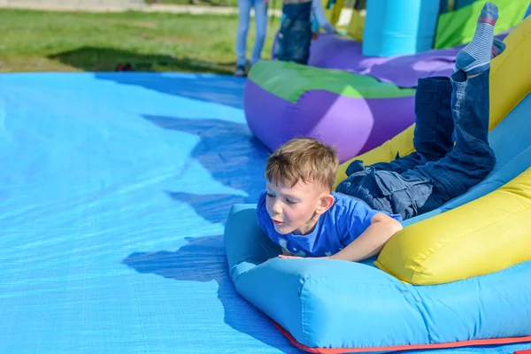 Yakışıklı küçük çocuk bir bouncy kale üzerinde yatıyor — Stok fotoğraf