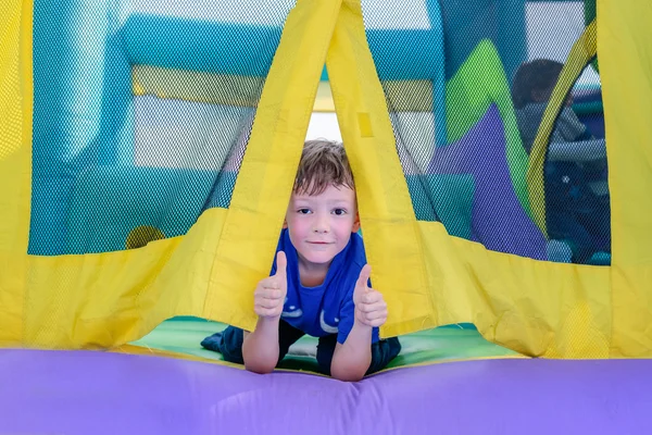 Curious boy looking from entrance of bouncy house — Stock Photo, Image