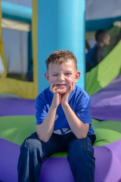 Pojke med svettiga ansikte sitter nära bouncy house — Stockfoto