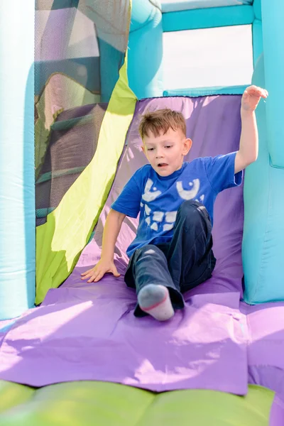 Cute boy sliding down inflatable ride — Stock Photo, Image