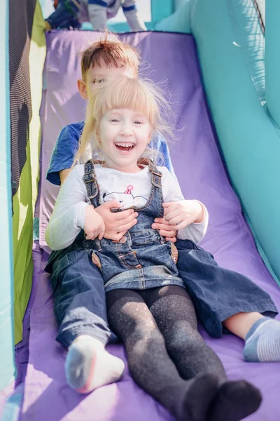 Kinderen gaan aan opblaasbare springkastelen dia Stockfoto