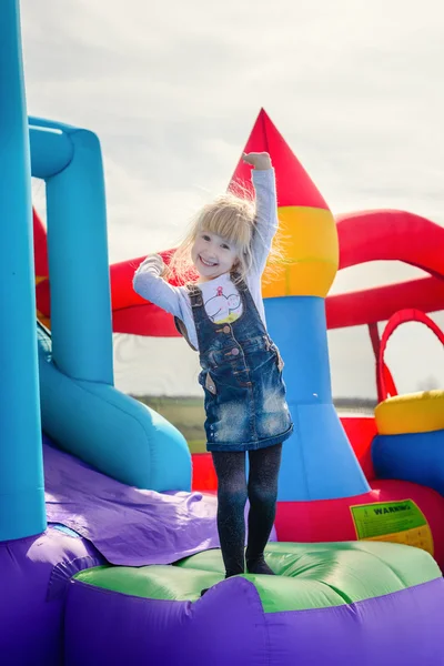 Menina excitada acenando da corrediça bouncy inflável Fotografia De Stock