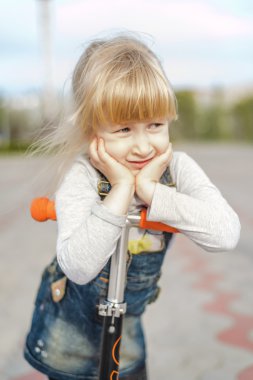 Bir oyuncak scooter üzerinde yorgun düşünceli genç kız