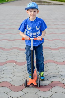 Bir oyuncak scooter üzerinde duran yakışıklı genç çocuk