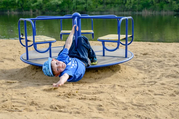 Menino em um giro alegre-go-round acenando — Fotografia de Stock