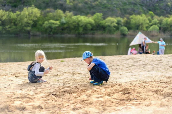 Hermano y hermana jugando en la arena cerca del río — Foto de Stock