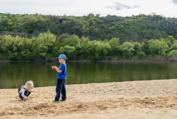 Garçon et fille jouer sur le sable près de la rivière — Photo