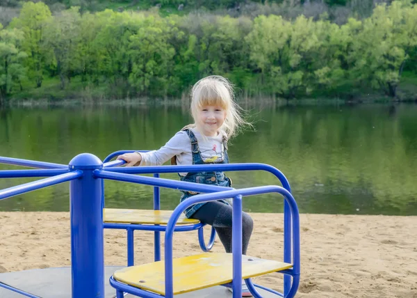 Jeune enfant jouant sur un manège bleu — Photo