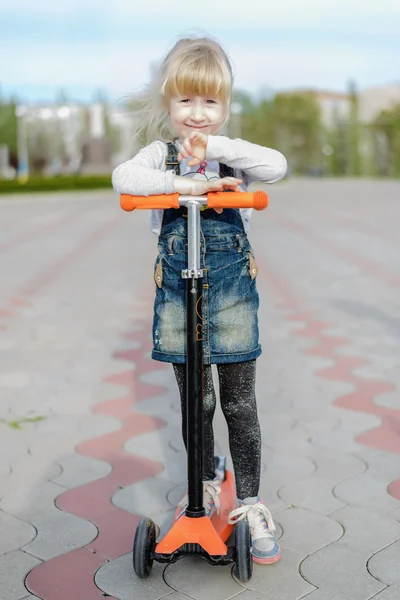 Cansado niña pensativa en un scooter de juguete — Foto de Stock