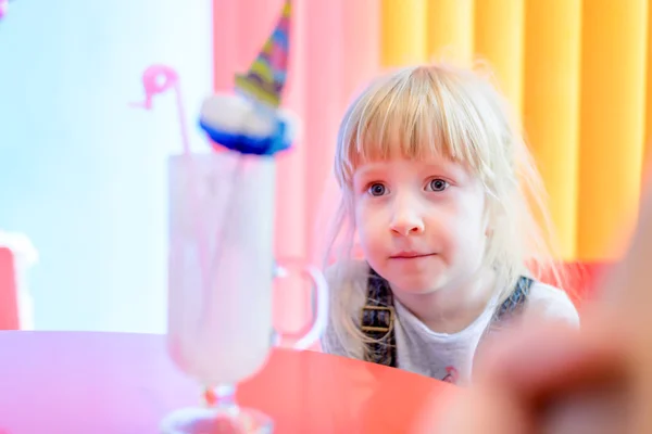 Linda menina loira bonita olhando um milkshake — Fotografia de Stock