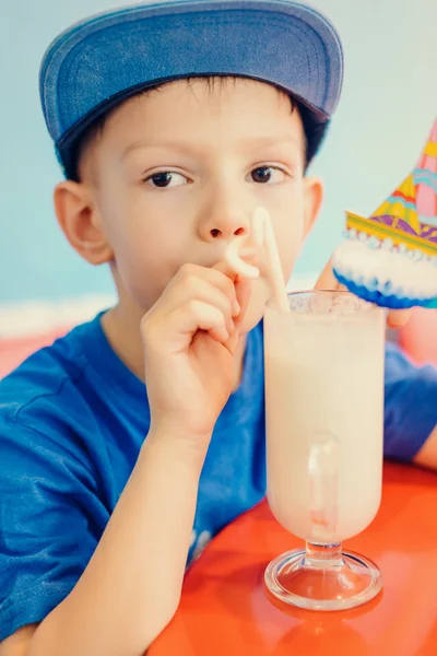 Серьезный маленький мальчик пьет молочный коктейль — стоковое фото