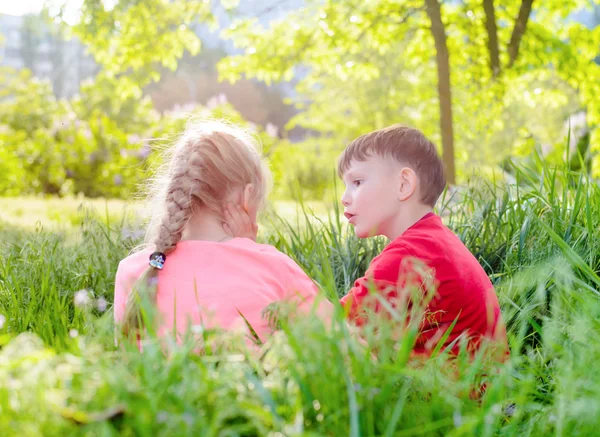 Dvě malé děti, které sedí chatování v zahradě — Stock fotografie