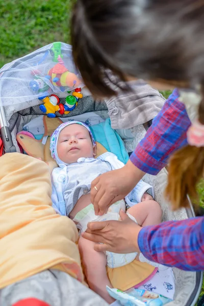 Moeder aanwezig zijn bij een kleine baby in een kinderwagen — Stockfoto