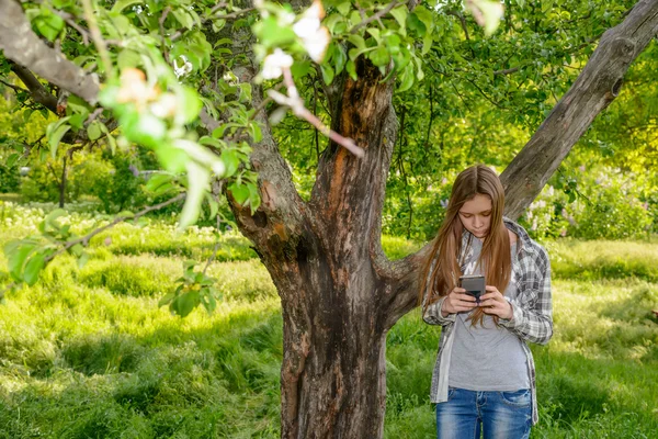 Alta esbelta joven chequeando su móvil — Foto de Stock