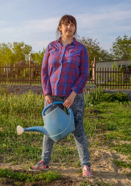Atrakcyjna kobieta stojąc podlewania sadzonek — Zdjęcie stockowe