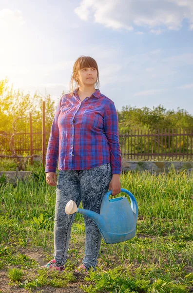 Mujer atractiva de pie regando plántulas — Foto de Stock