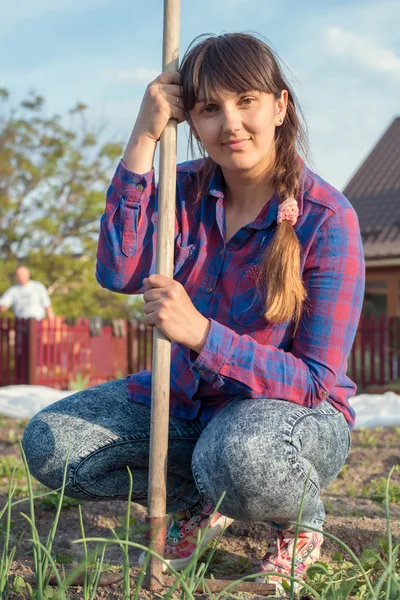 Middle-aged female gardner leaning on her rake — Stock Photo, Image