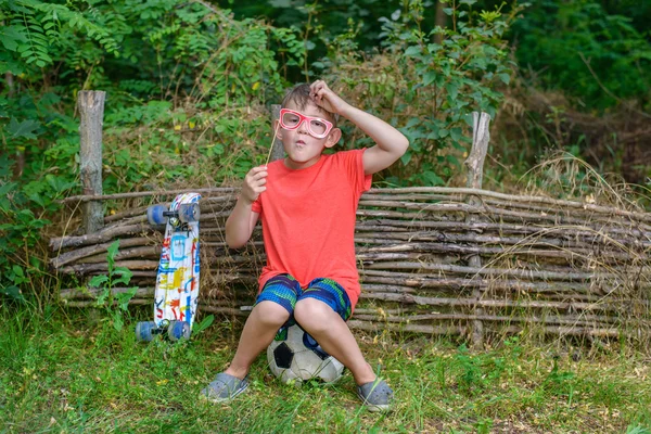 Legrační malý chlapec hraje s photo booth rekvizity — Stock fotografie