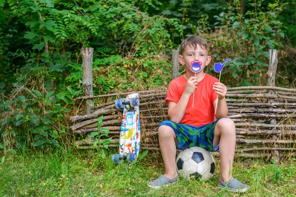 Junge hält Spielzeugpfeife und scherzhafte Symbole in der Nähe des Mundes — Stockfoto