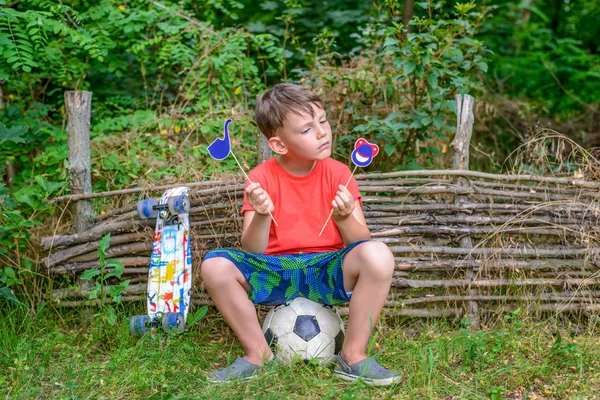 Befuddled boy with symbols on sticks outside — Stock Photo, Image
