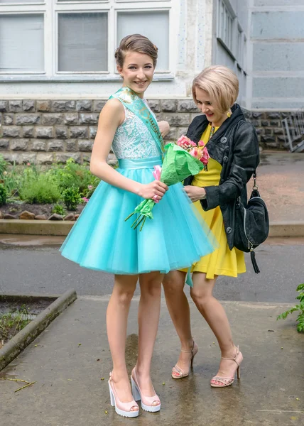 Гордая мать помогает дочери с платьем на улице — стоковое фото