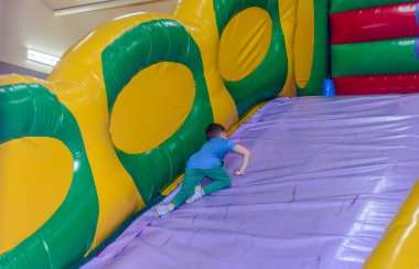 Küçük çocuk bir bouncy kale slaytta aşağı doğru kayar