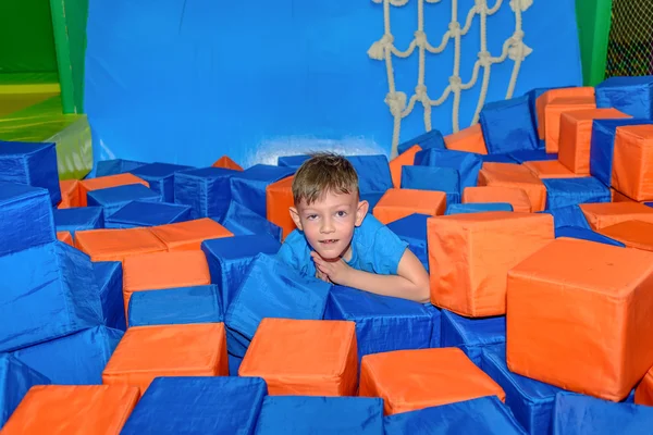 Cute happy little boy crouched down amongst cubes — Stock Photo, Image