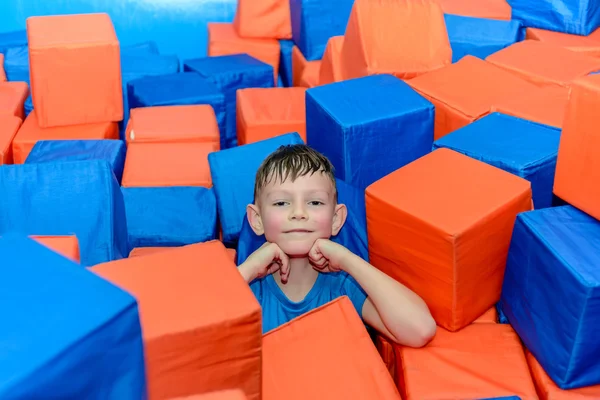 Cute happy little boy crouched down amongst cubes — Stock Photo, Image