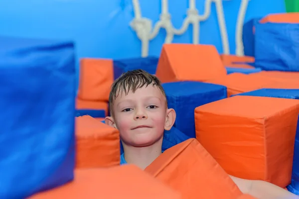 Lindo niño feliz agachado entre cubos — Foto de Stock