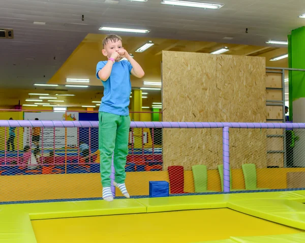 Sprudlande ung pojke studsande på en studsmatta — Stockfoto