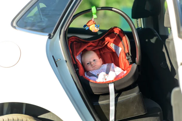 Sleepy little baby in a carrycot in a car — Stock Photo, Image