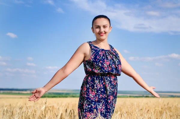 Kvinnan stående njuta av solen i ett vete fält — Stockfoto