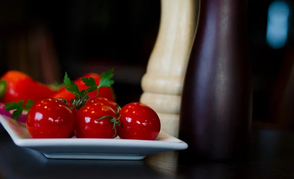 Teller mit roten Tomaten mit Salz- und Pfeffermühlen — Stockfoto