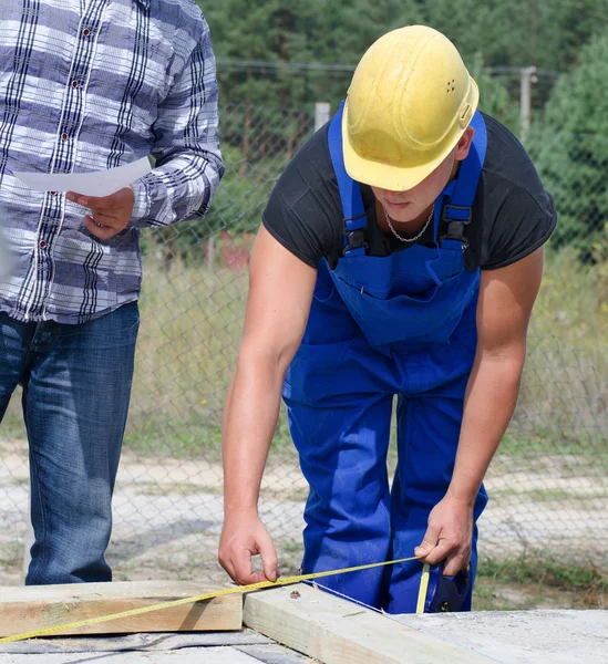 Builder measuring a wooden beam — Stock Photo, Image