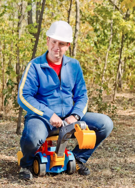 Father riding on his kids toy excavator — Stock Photo, Image