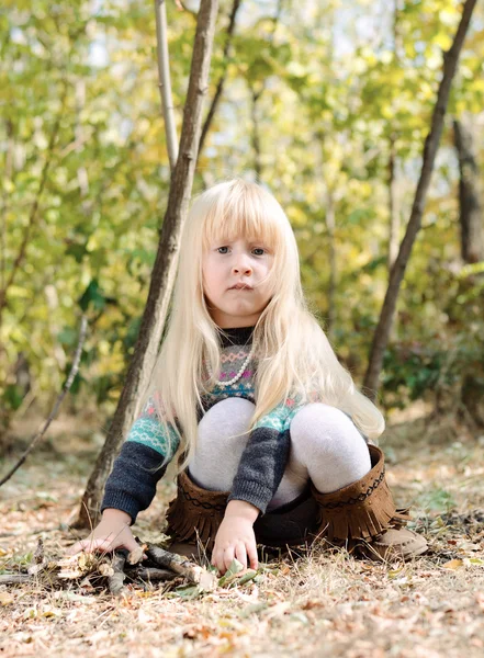 Adorable niña sentada en el suelo del bosque —  Fotos de Stock