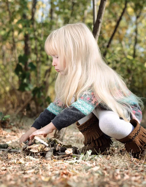 Niña rubia jugando con palos secos —  Fotos de Stock