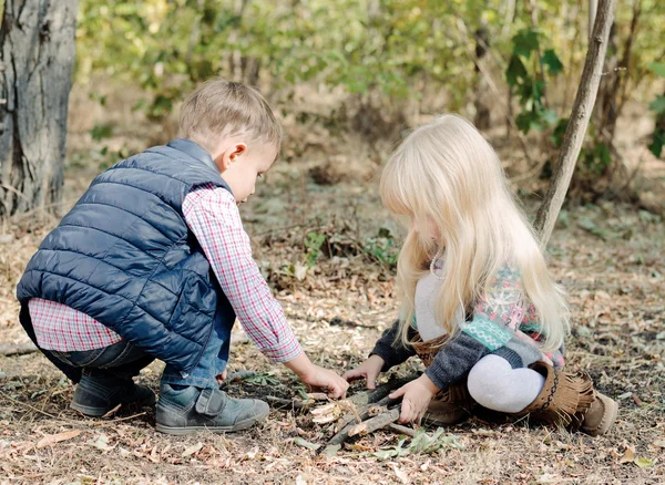 Söta småbarn leker med torra pinnar på marken — Stockfoto